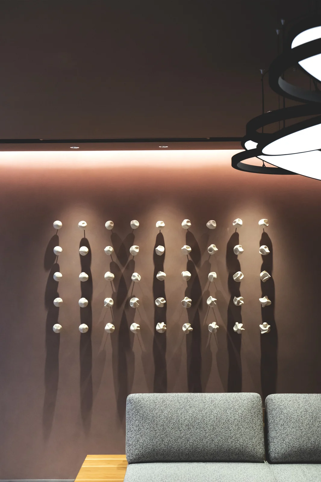 Forty-five white porcelain forms mounted above seating in an interior
