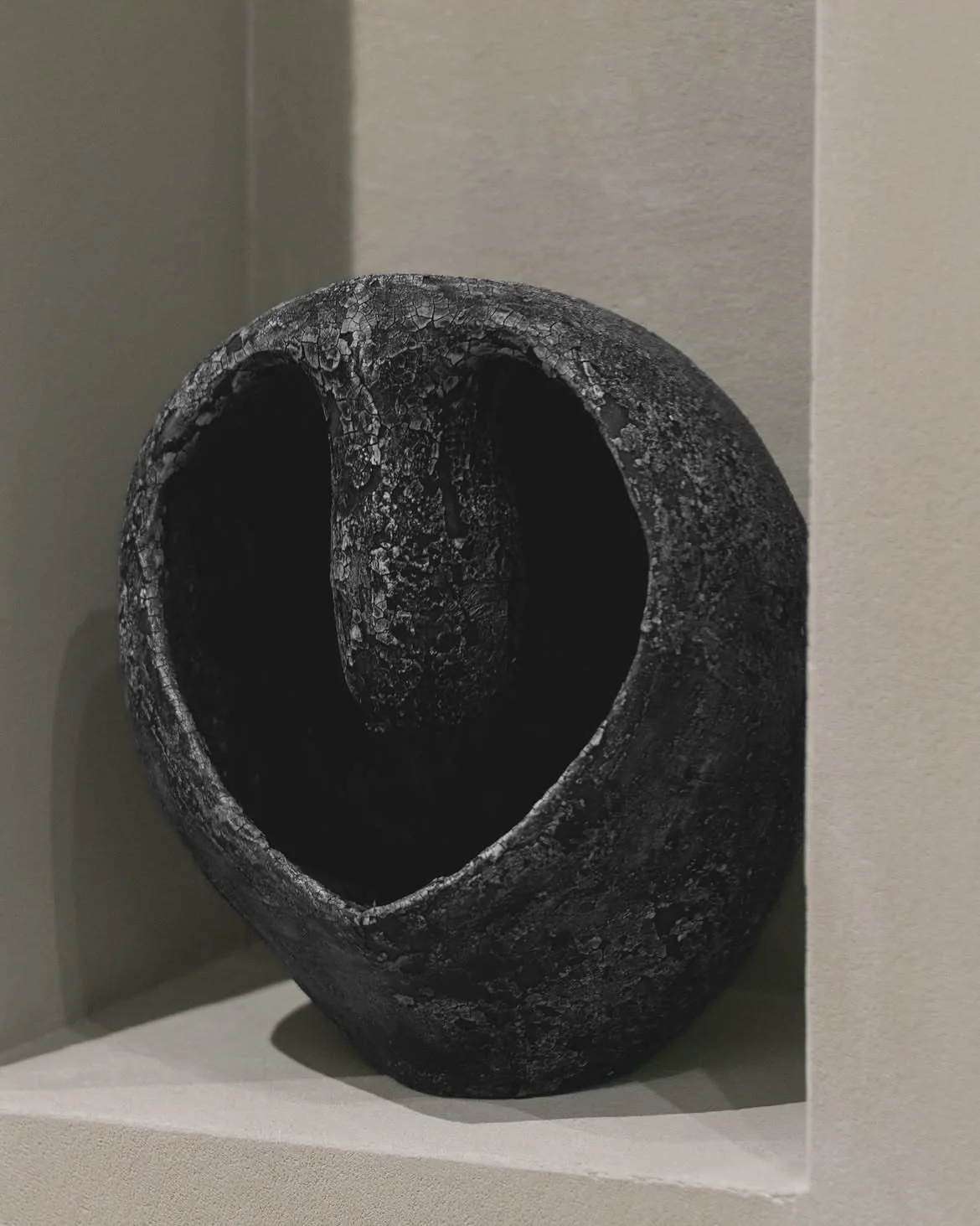 A dark circular ceramic sculpture in a recessed niche