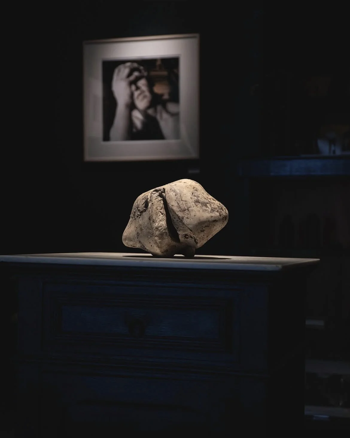A small stone-colored sculpture on a dark cabinet