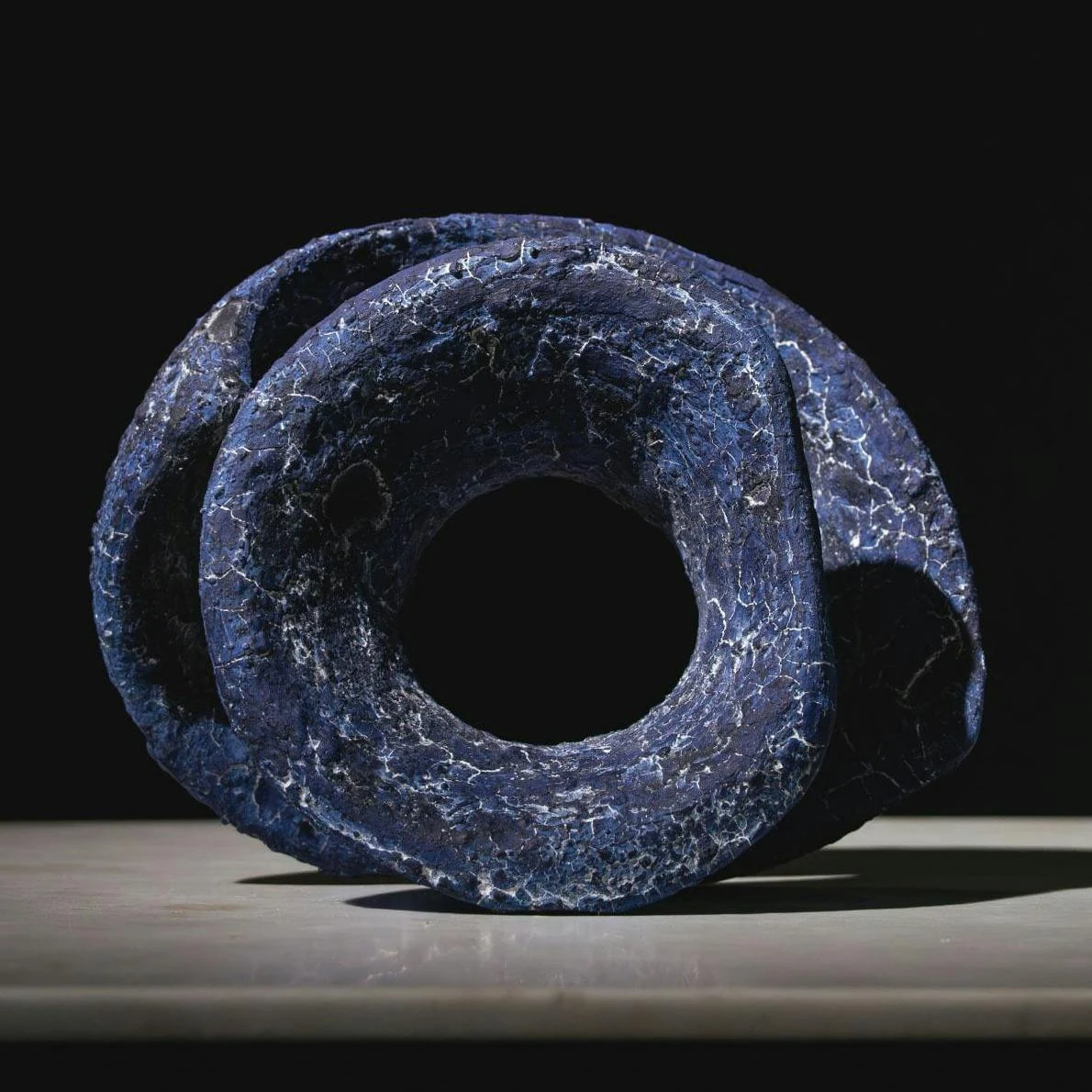 A blue sculptural form shaped around a central opening.