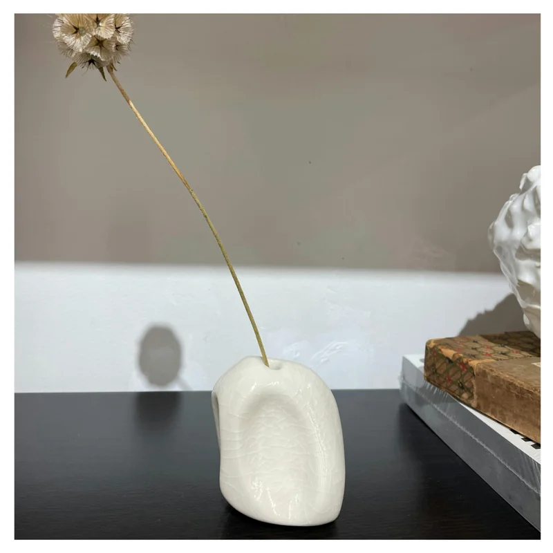 A small porcelain object for incense or a single dried stem.