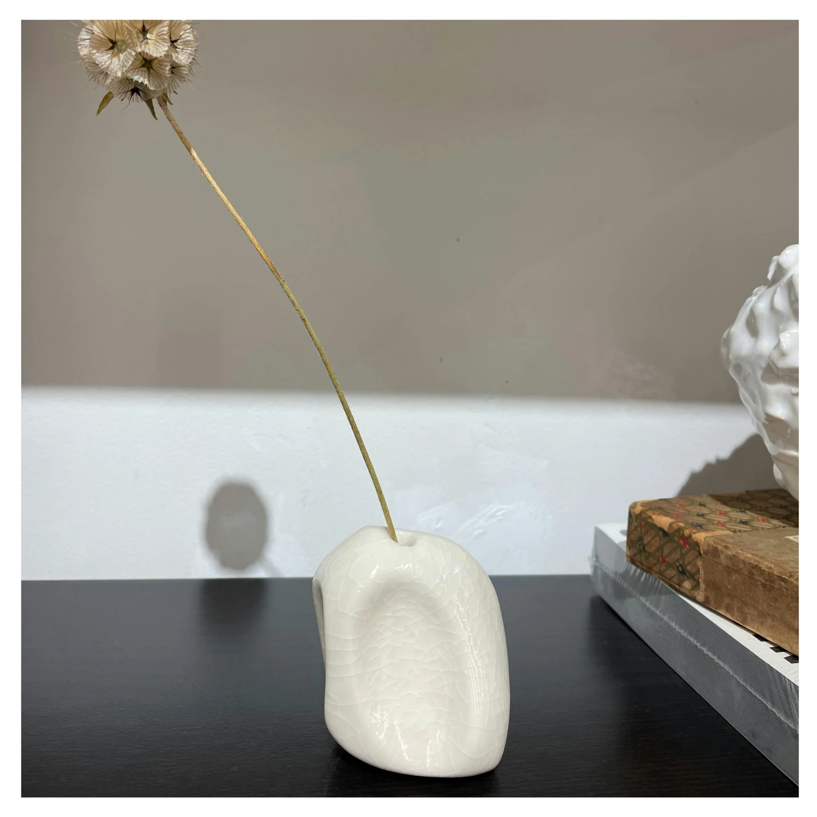 A small porcelain object for incense or a single dried stem.