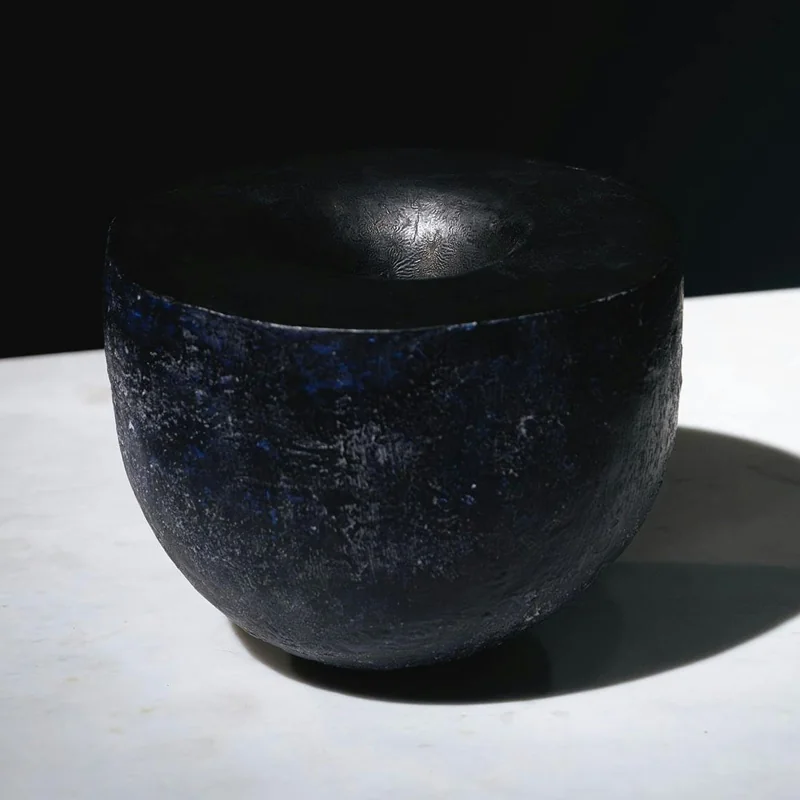 A dark vessel with a blue surface and a reflective interior.