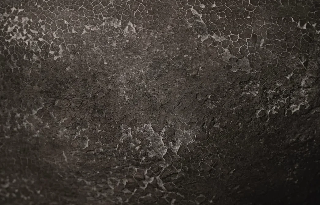 A dark ceramic surface traced with a network of cracks