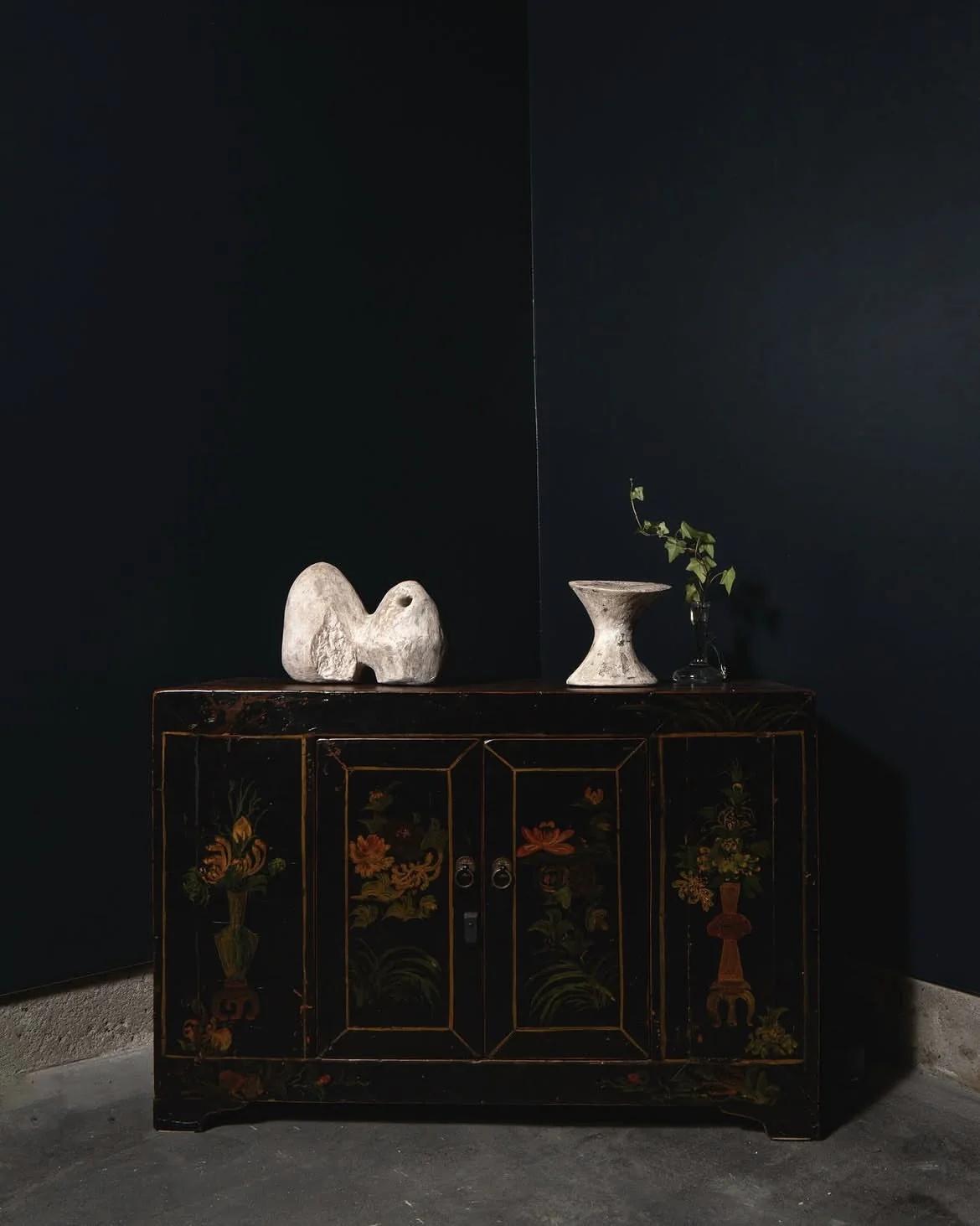 White sculptures placed on a wooden cabinet in a dark room